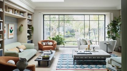living room furniture arranging mistakes, neutral living room, crittall doors view of garden, armchairs and couches, large coffee table, rug, bookcases, skylight 