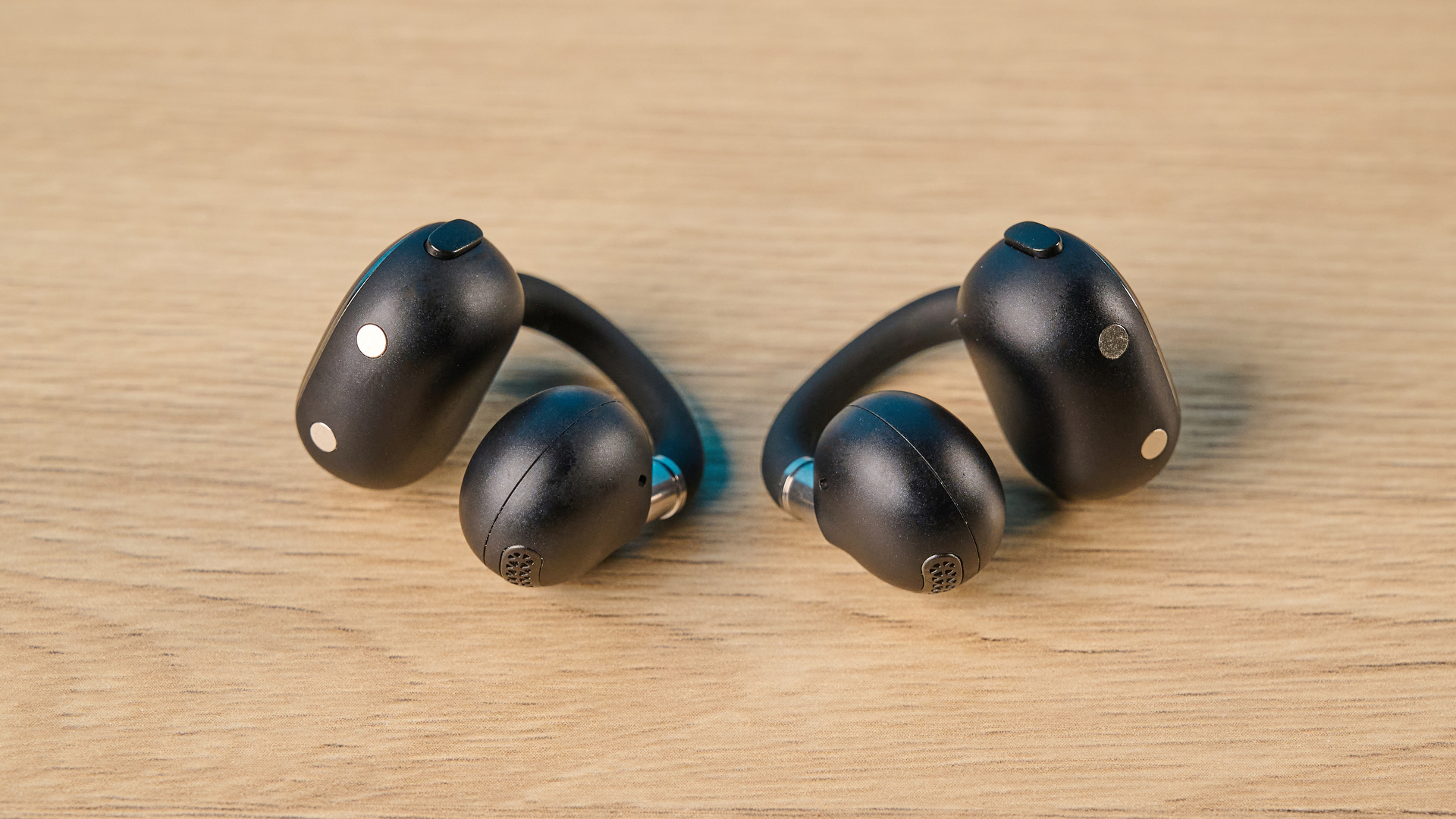 EarFun Clip 2 in black on table photographed in front of a blue background