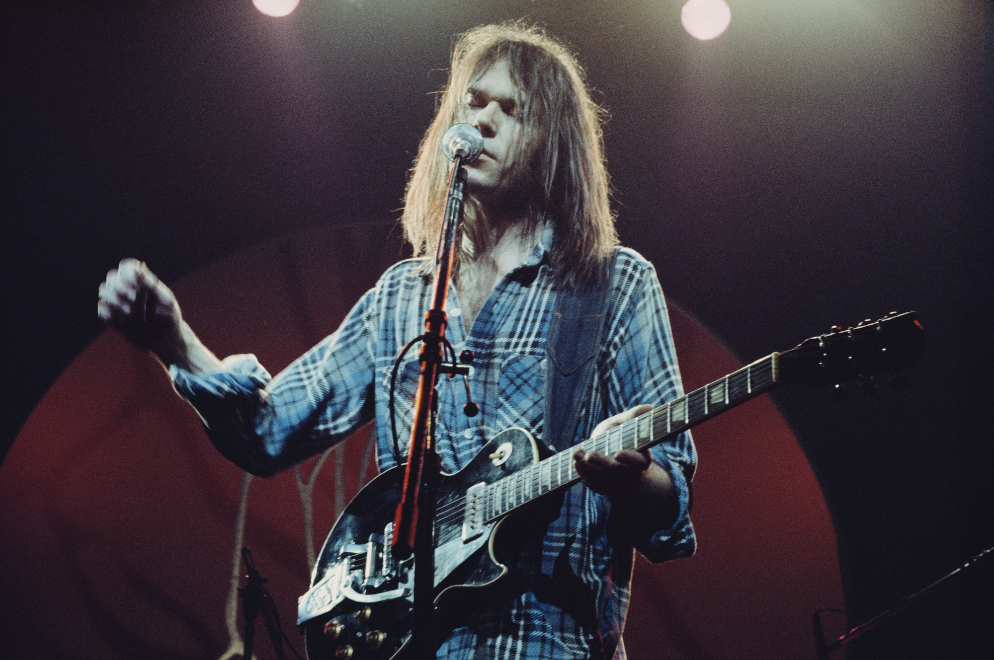 Neil Young performs on stage with Crazy Horse at the Hammersmith Odeon in London on March 28, 1976