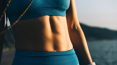 Woman's abs pictured close up in blue activewear
