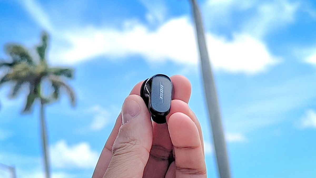 Bose QuietComfort Earbuds 2 held aloft between reviewer&#039;s finger tips