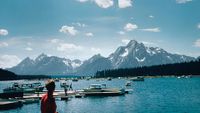 a meteorite is seen falling to Earth during a bright sunny day over a mountain range and lake.