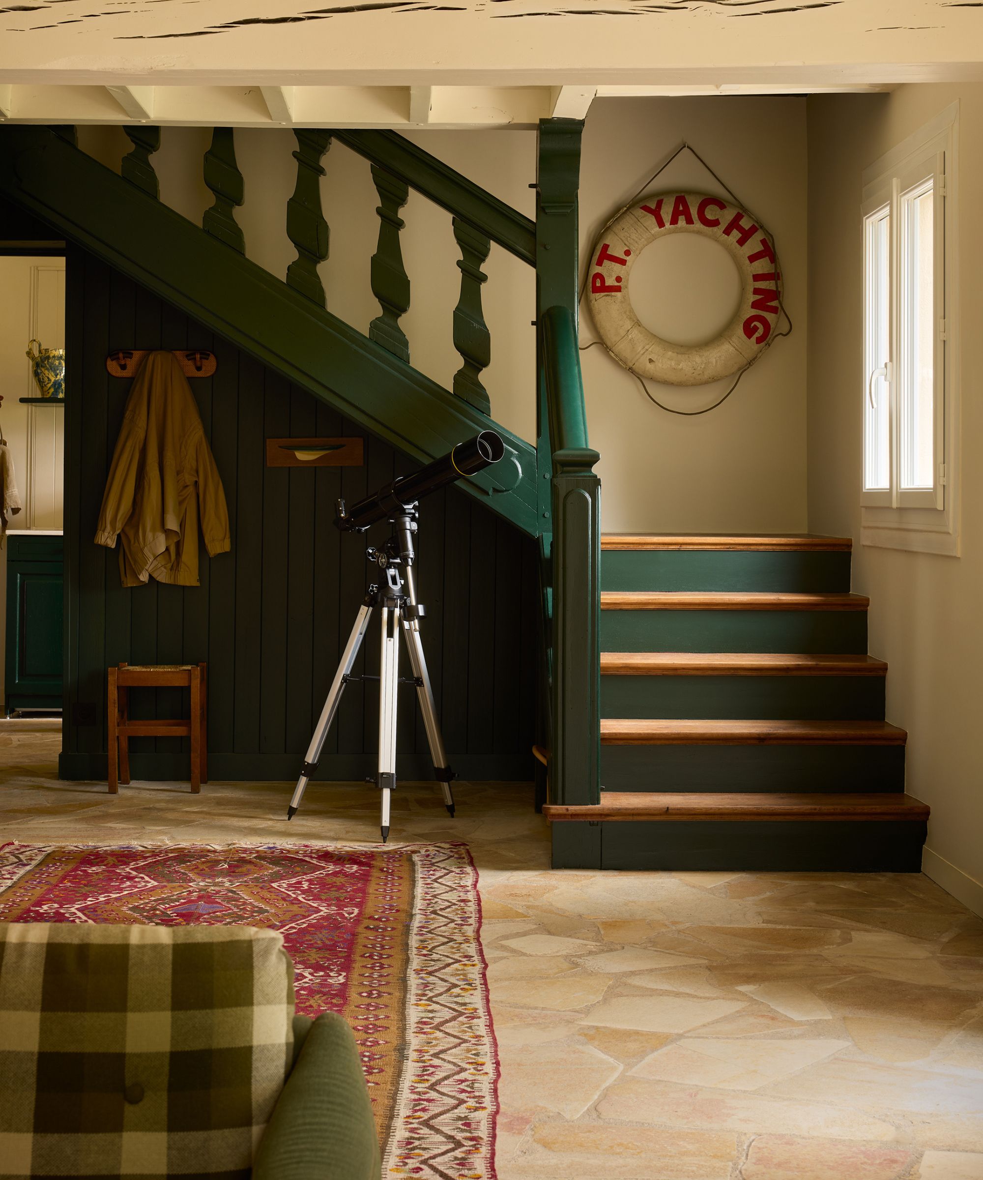 a rustic cottage in France with dark green staircase, vintage nautical decor and a red vintage rug