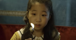 Player 456's daughter holding a lighter shaped like a gun