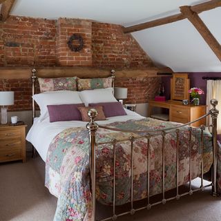 attic bedroom with brick walls and wooden bedside table