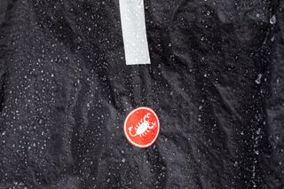 Close up of water droplets on Castelli Squall Shell showing logo and reflective stripe