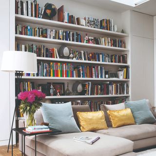 A living room with a corner sofa and tall built-in bookshelves behind it
