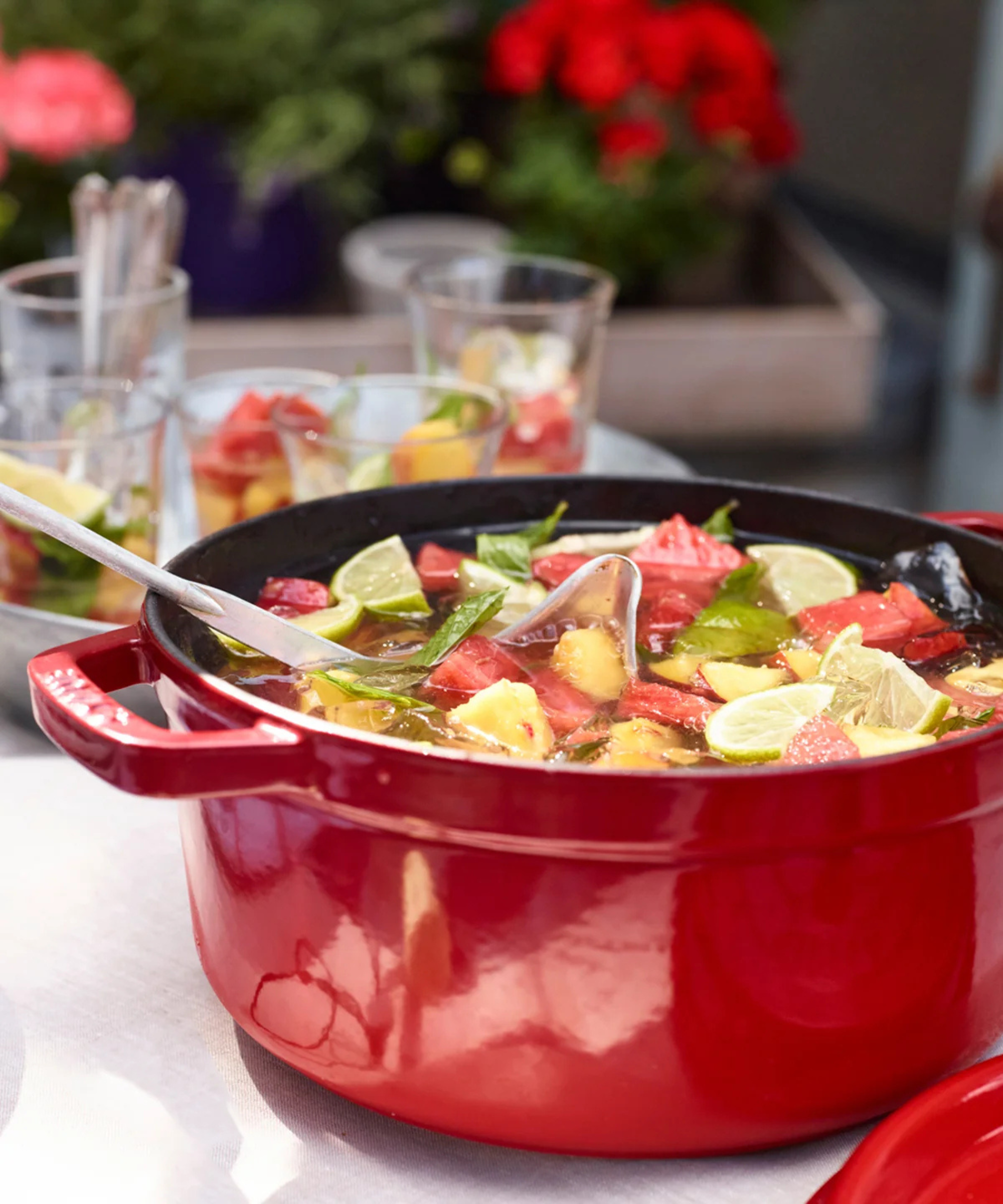 Staub Cast Iron Cocotte in cherry red, holding a fruity summer punch