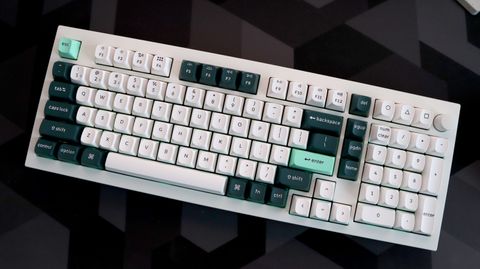 A Keychron Q5 HE gaming keyboard on a desk with white and blue keycaps.