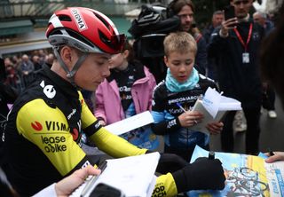 Team Visma-Lease a Bike's Danish rider Jonas Vingegaard (L) signs autographs prior to the 4th stage of the Paris-Nice cycling race, 163,4 km between Vichy and La Loge des Gardes, on March 12, 2025. (Photo by Anne-Christine POUJOULAT / AFP)