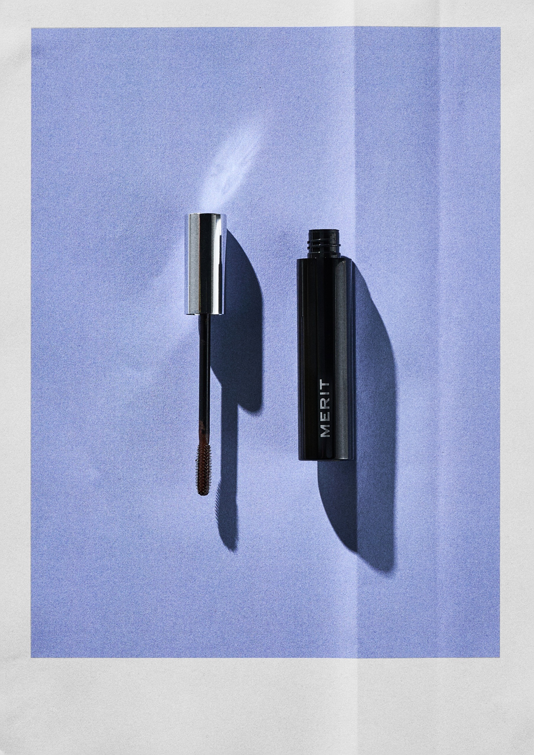 The Merit Clean Volume Volumizing Tubing Mascara on a blue background