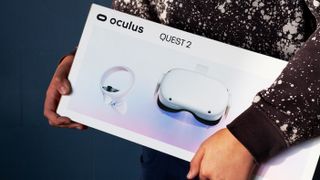 Eine Person, die eine Schachtel mit einem Oculus Quest 2 VR -Headset im Inneren trägt