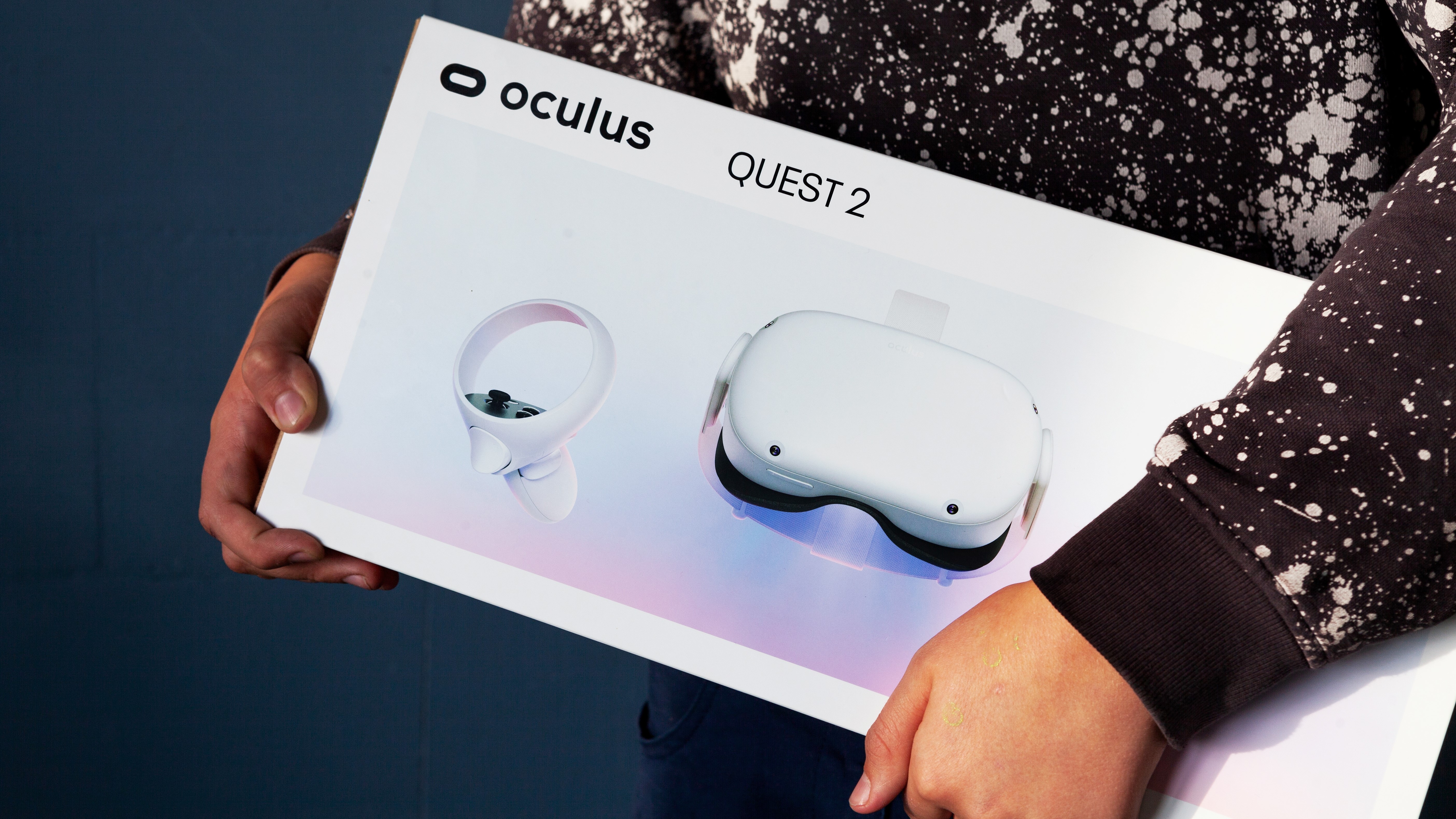 Une personne porte une boîte contenant un casque VR Oculus Quest 2 en