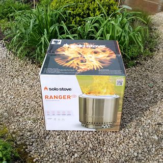 The stainless steel Solo Stove Ranger fire pit being assembled in a gravel garden