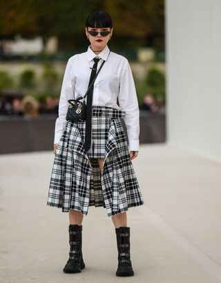 woman wearing a checked skirt white shirt and black tie