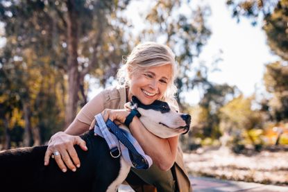  woman enjoying walk in nature and embracing pet dog
