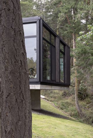 The primary bedroom suite cantilevers over the concrete plinth at the east end of the house