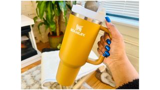 A person holding a gold 40oz Stanley Quencher Tumbler for Stanley Quencher Tumbler review.