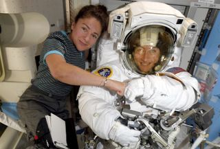 NASA astronaut Jessica Meir (left) gives her colleague Christina Koch a fist bump during a spacesuit check at the International Space Station ahead of their historic all-woman spacewalk.