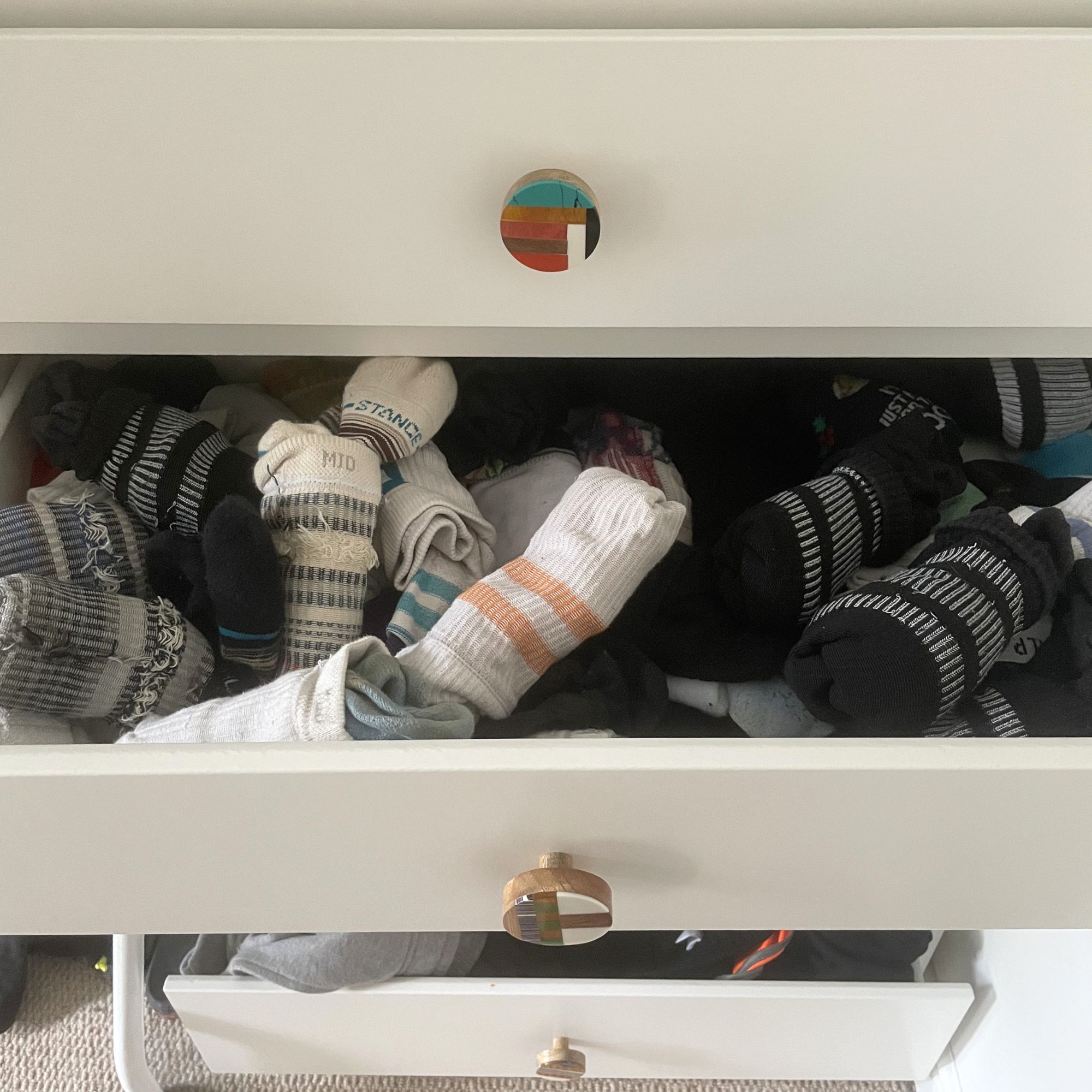 Messy socks in a white chest of drawers