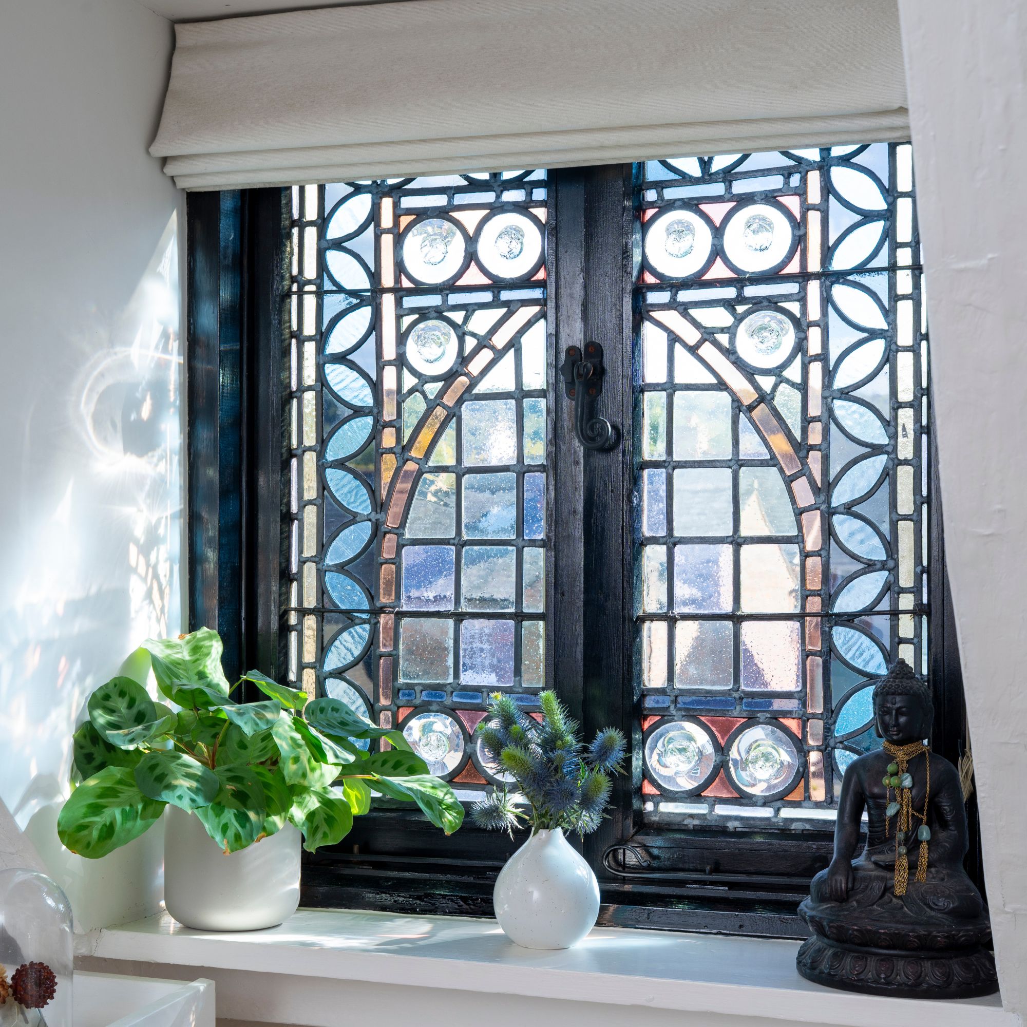 A small stained glass window with a roller blind on top