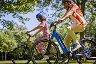 Woman and man riding Raleigh Motus e-bikes in a park
