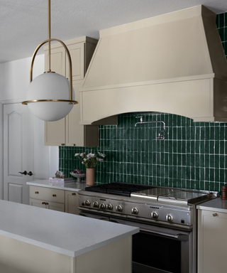 A kitchen with dark green tile backsplash and warm neutral features