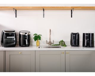 A selection of air fryer appliances from Tower, Lakeland, T-fal and Dreo in modern grey kitchen on countertop