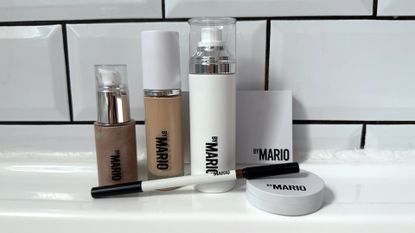 A selection of the best Makeup by Mario products stood a white surface against a white tiled background