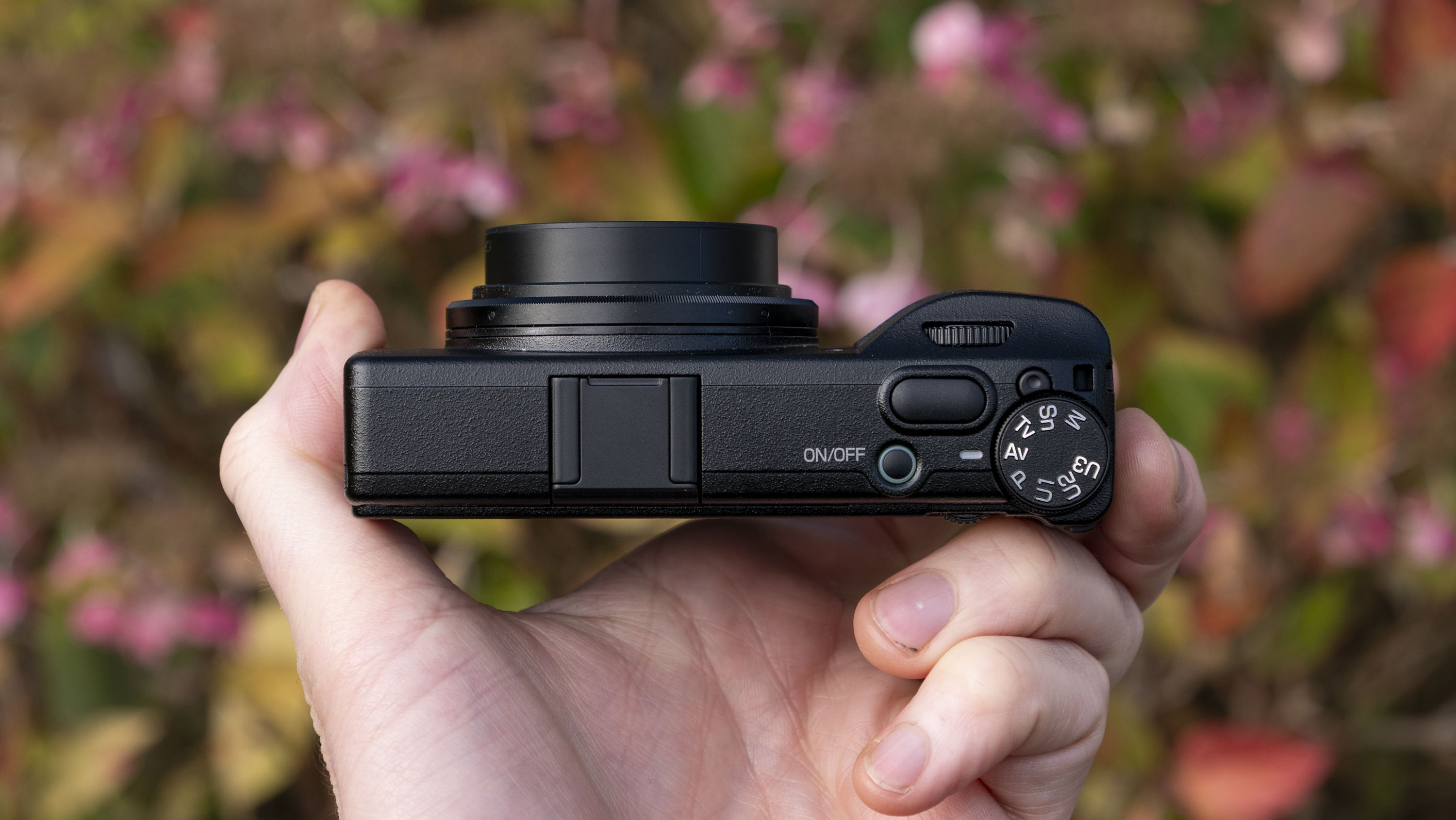 Ricoh GR IV compact camera in user's hand, view of the top