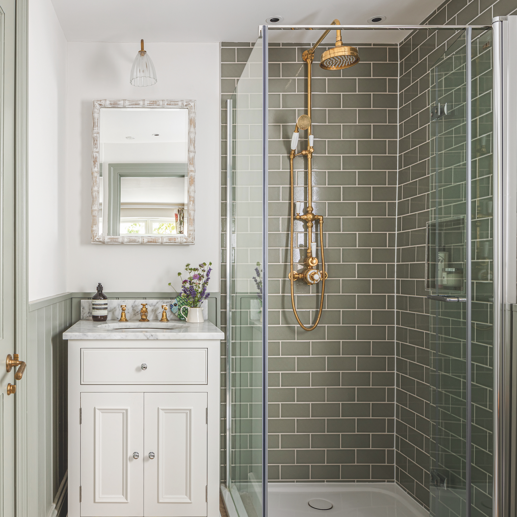 shower room with white vanity unit with marble top and shower enclosure with green metro tiles and brass shower fitting