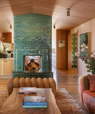 A living room with a teal tiled fireplace and wooden floors, walls and ceilings