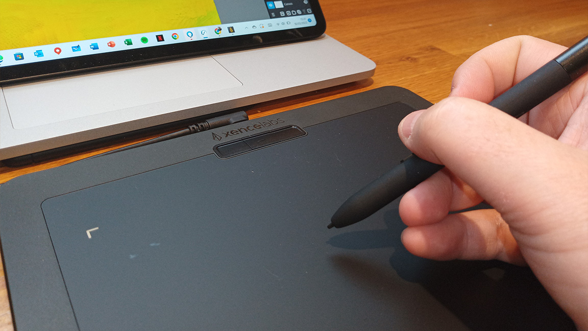 Xencelabs Pen Tablet Small review; a person's hand holds a pen stylus over a small drawing tablet
