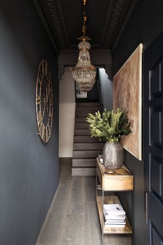 Grey entryway with a large painting and console table decorated with foliage in a vase