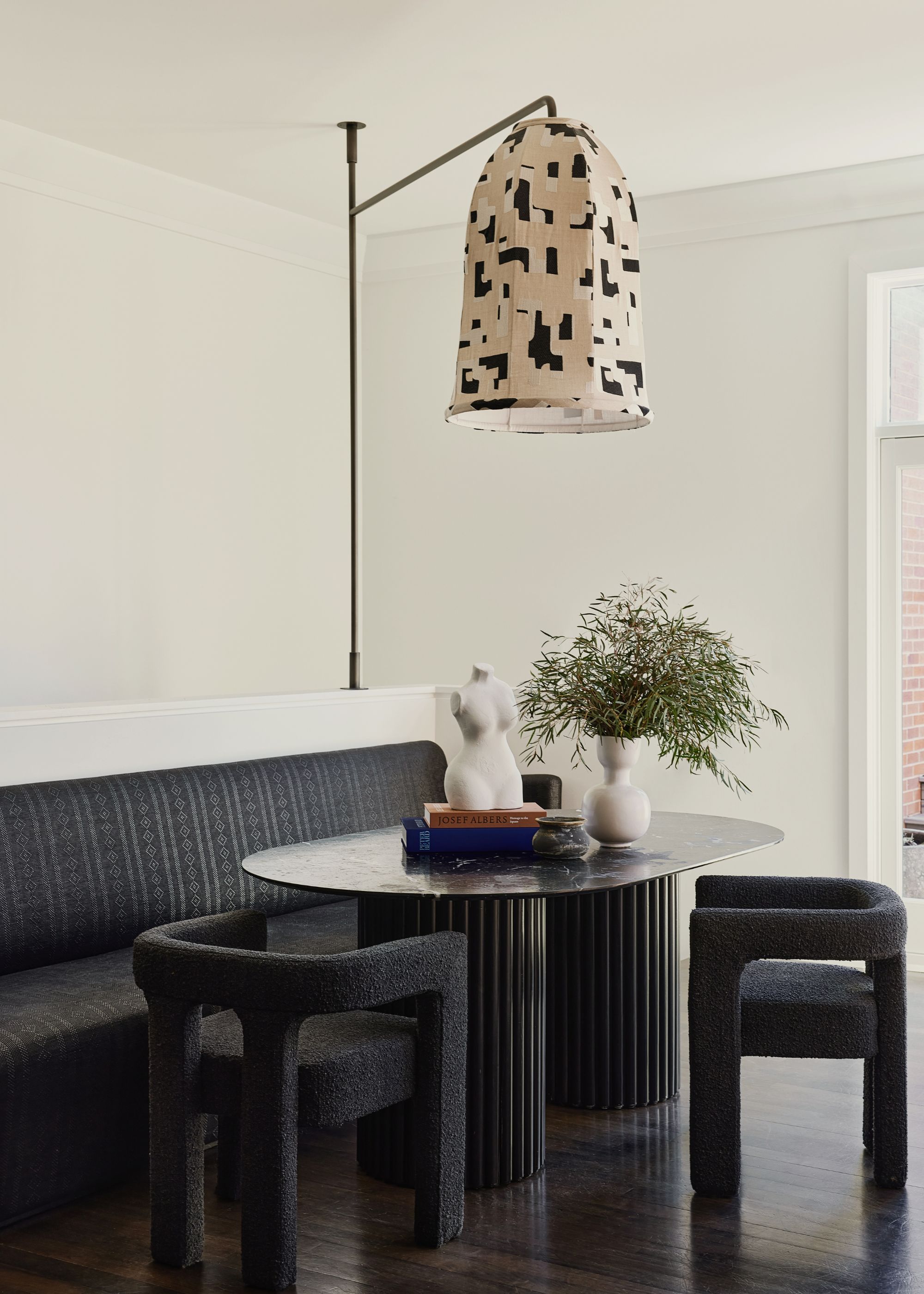 A banquette next to the dining room, with a sofa, two chairs and a custom light