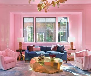 living room with barbie pink walls and gold coffee table pink armchairs