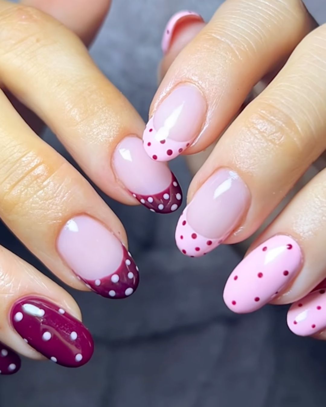 Pale pink and burgundy polka dot nails.