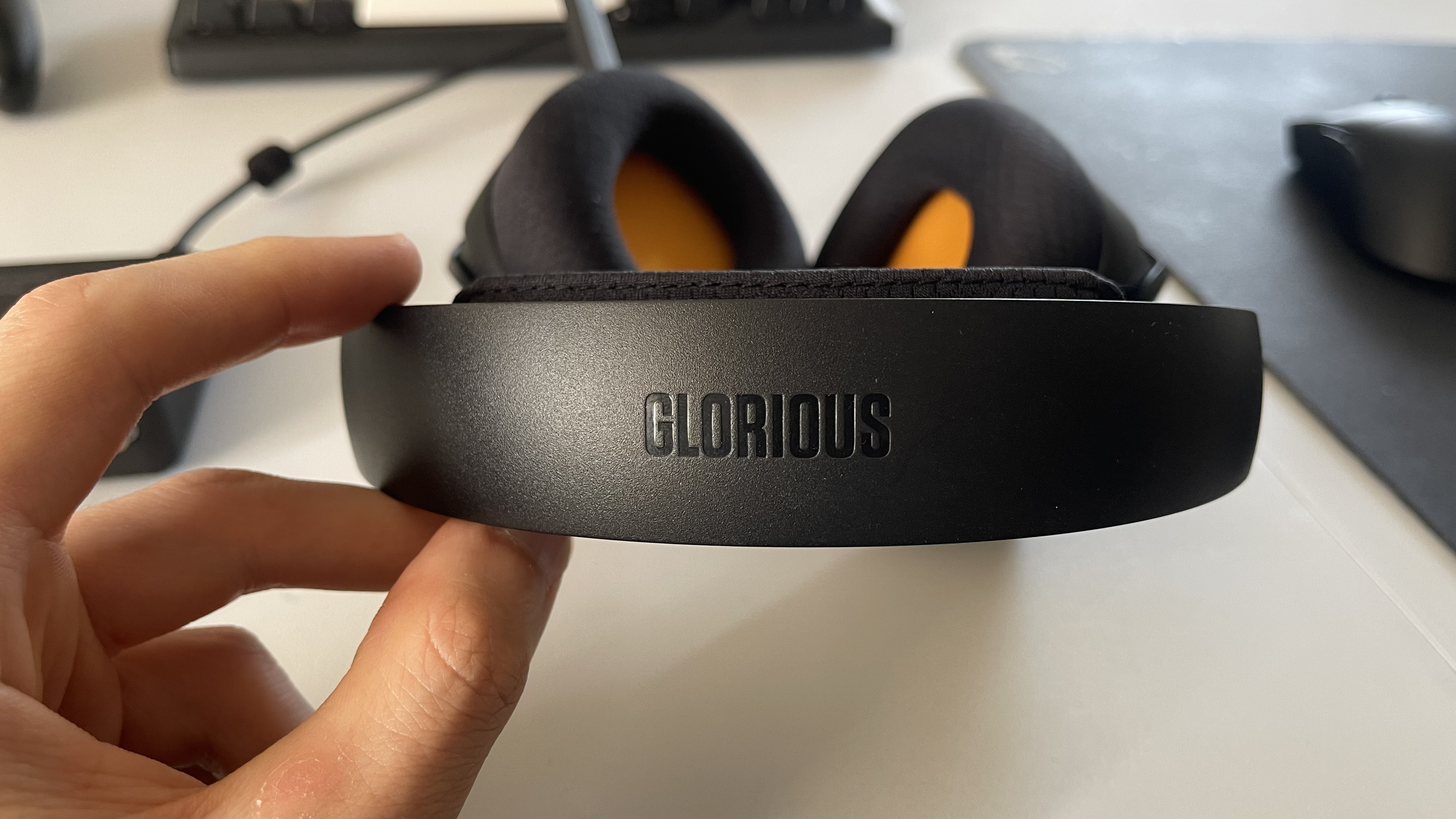 The Glorious GHS Wireless InfinitePlay gaming headset in black and orange on a plain white desktop.