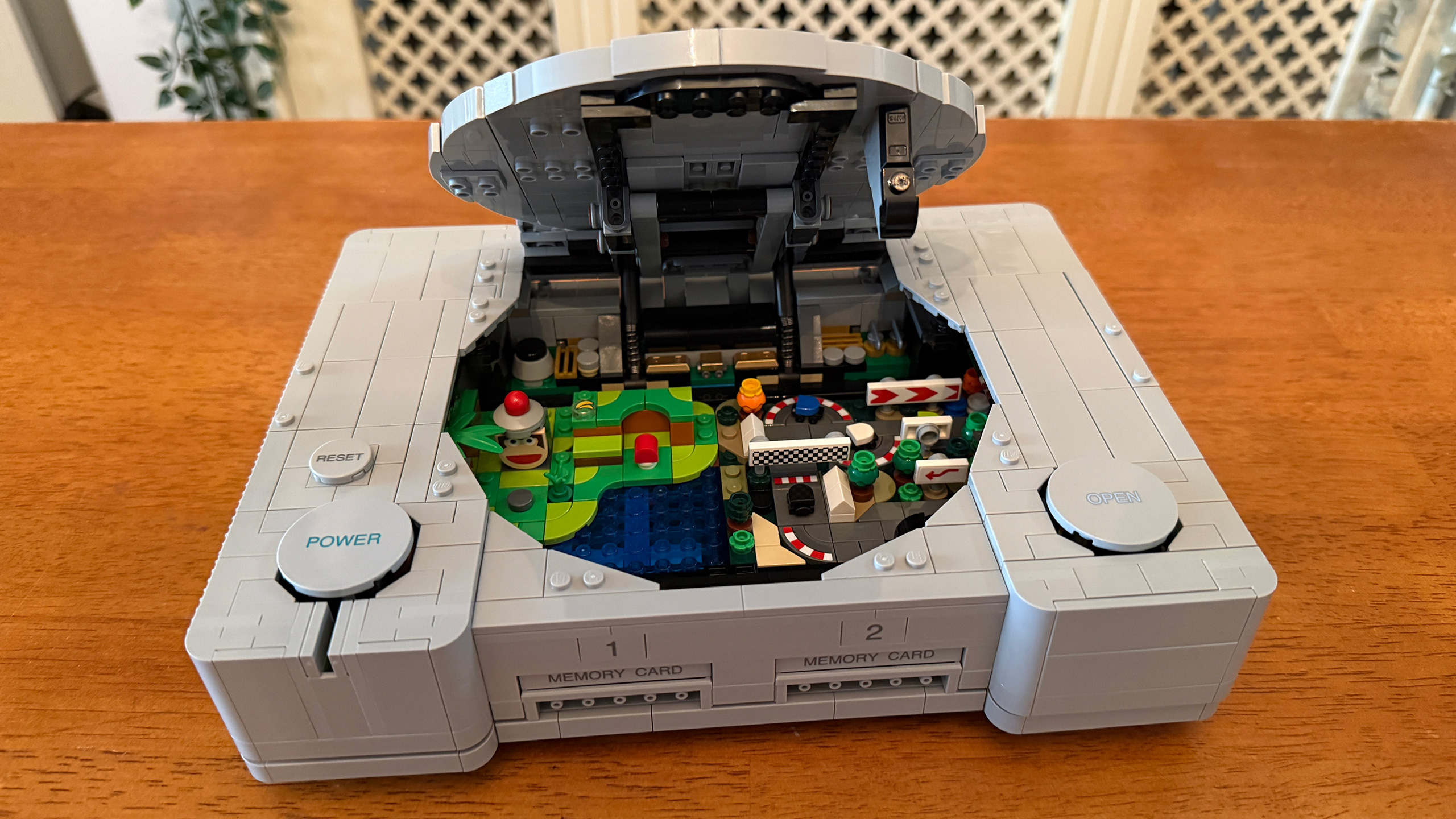 The Lego PlayStation #72306 with disc tray lid open showing dioramas inside