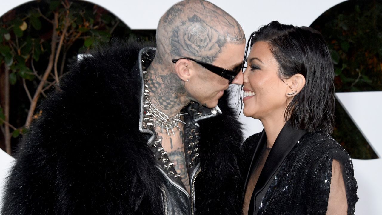 Kourtney Kardashian Barker and Travis Barker kiss on a red carpet