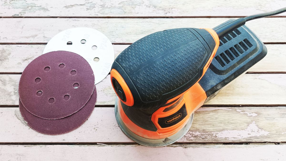 Orbital sander and sanding pads on wooden table