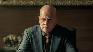 Michael Cudlitz's Lex Luthor seated and wearing a business suit