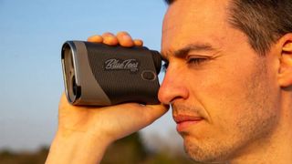 A golfer puts the Blue Tees Series 3 Max Laser Rangefinder to his eyes