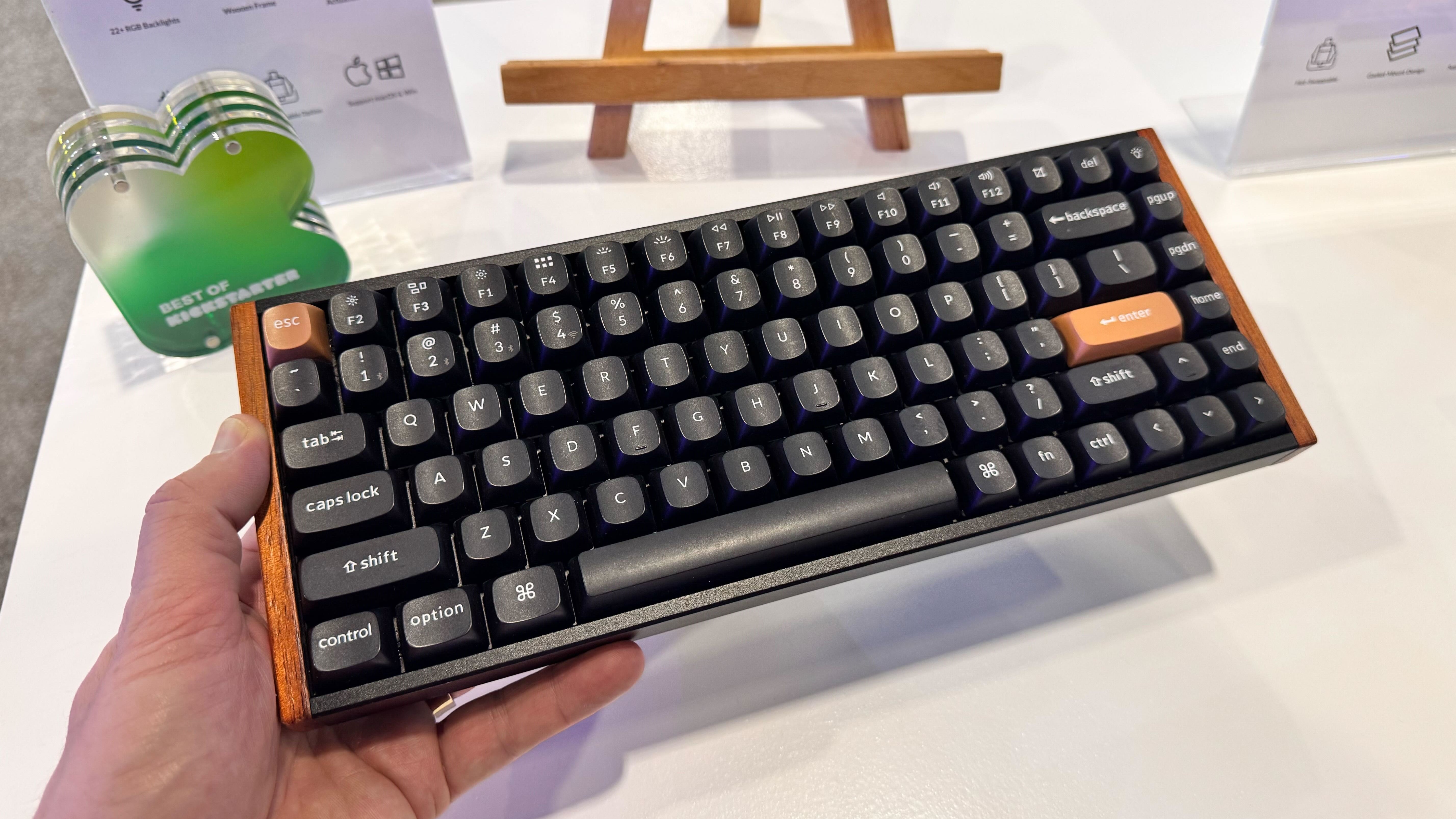 CES 2025の白いテーブルの前で手に持つKeychron K2 HE