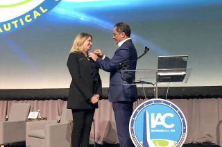 Michael Lopez-Alegria, representing the Association of Space Explorers, awards Virgin Galactic chief astronaut instructor Beth Moses with a Universal Astronaut Insignia.