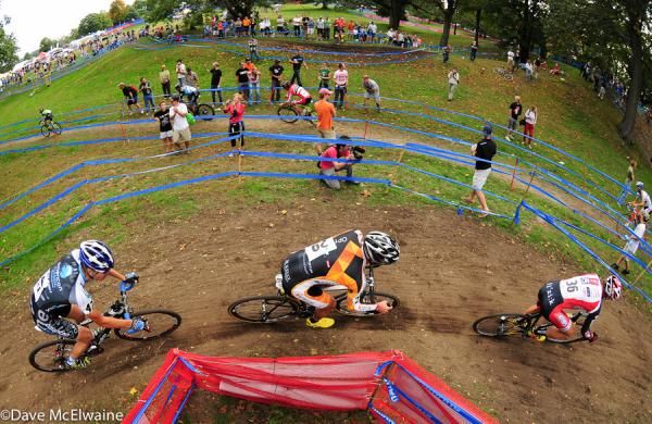A pack of riders rounds the corner to the uphill barriers