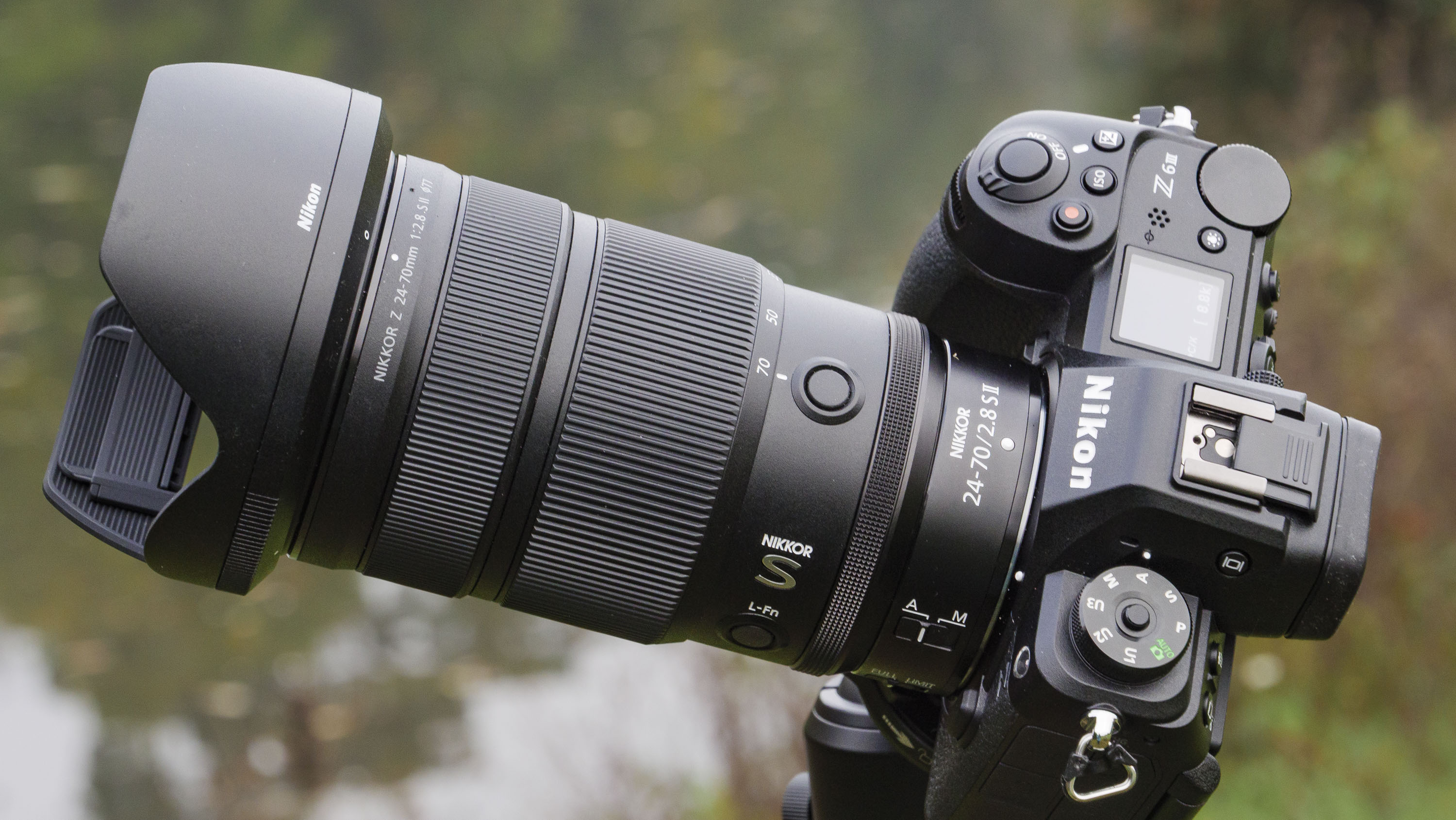 Nikon Z 24-70mm f/2.8 S II lens mounted to a tripod with autumnal lake background