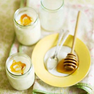yogurt with honey in glass jar and yellow plate