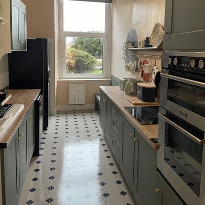 painted kitchen with green cabinets and tiled floor