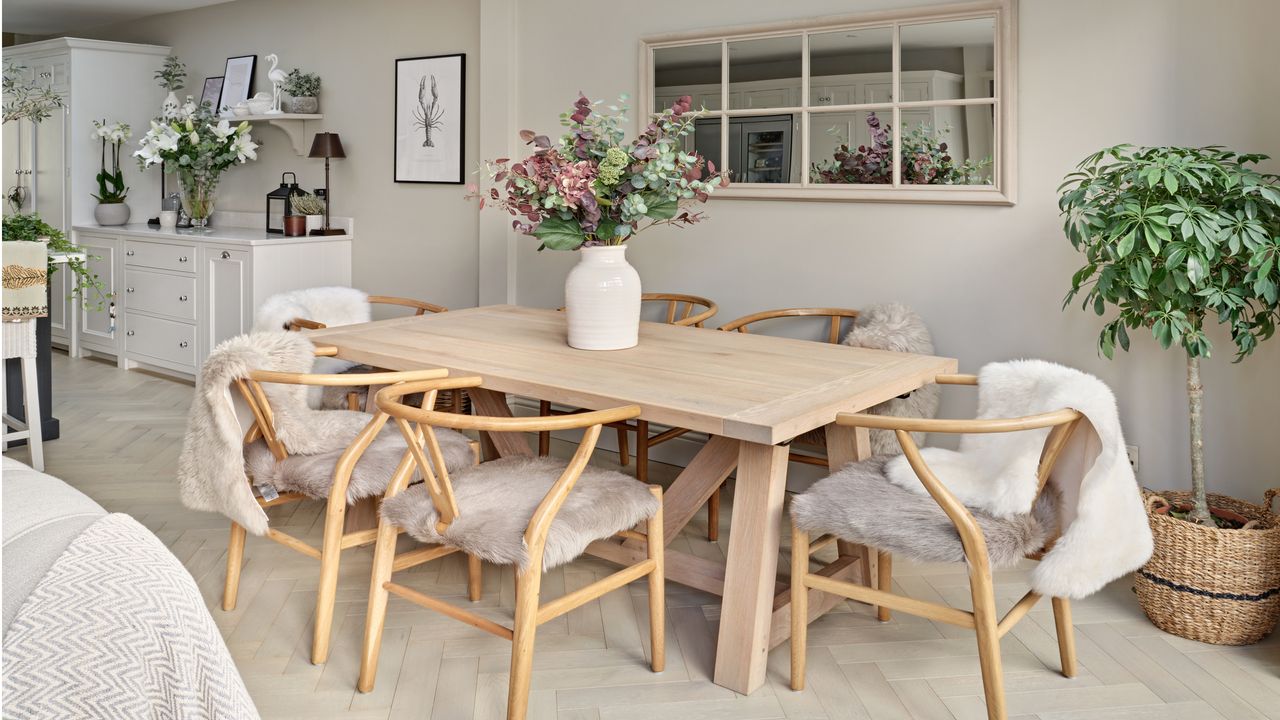 wooden dining table and chairs on wooden flooring with cream walls, white drawers and plant in woven basket